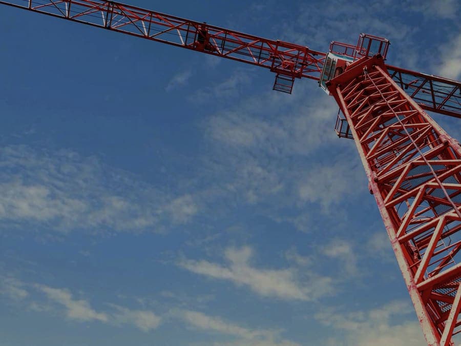 Red tower crane jib seen from below against an open sky